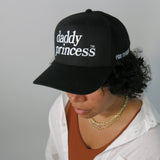 Person wearing a black cap with 'daddy princess' text on a plain background